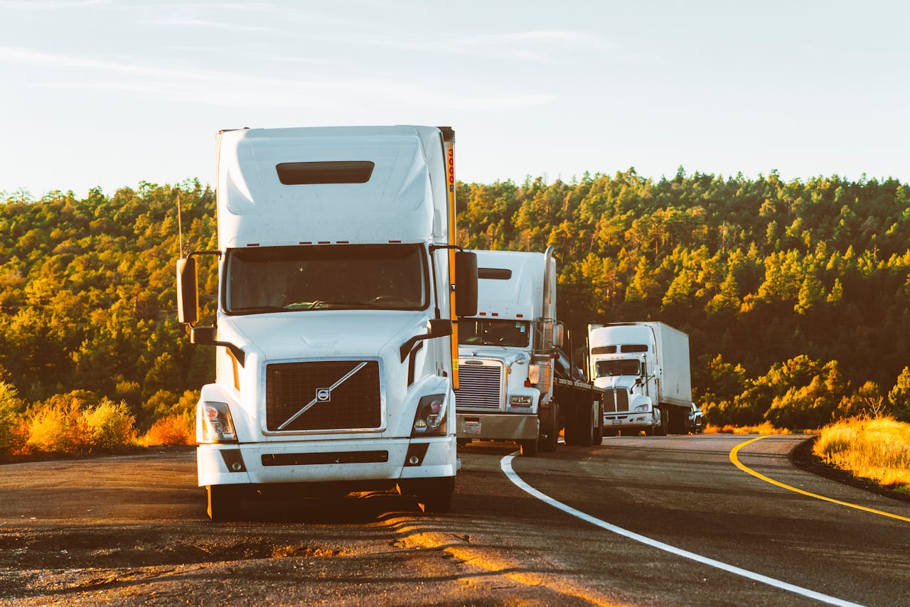 heros-img Three semi trucks driving on a highway through a forested landscape in Arizona.